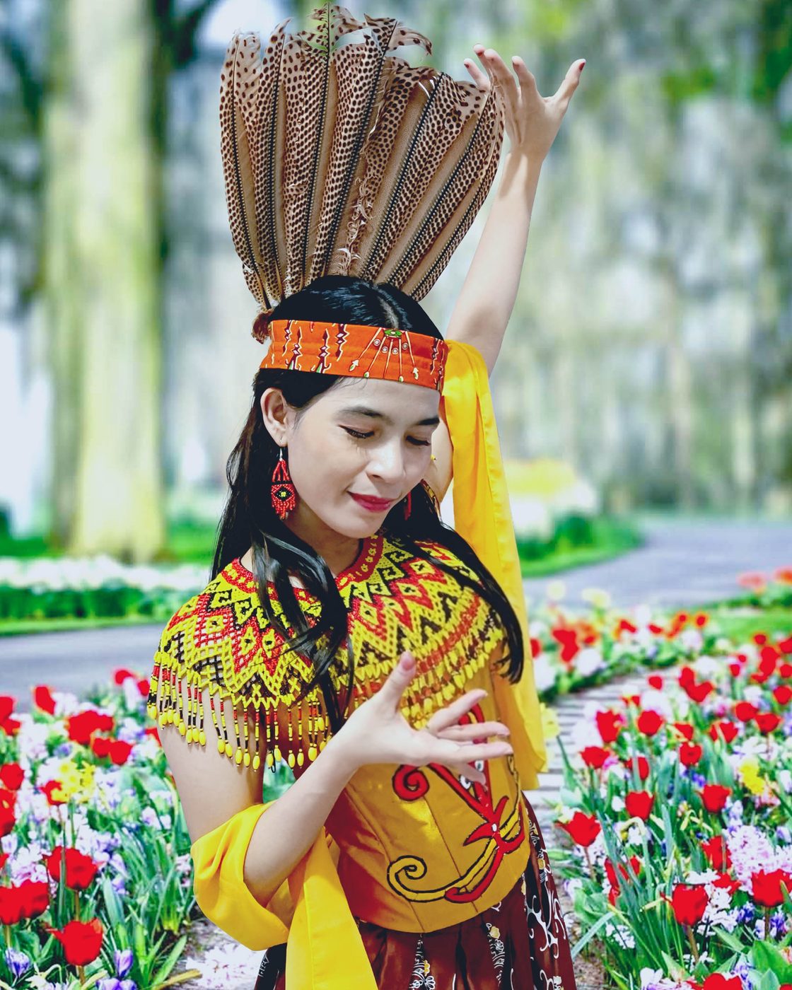 Model Veina Skincare mengenakan busana adat Dayak di taman berbunga Kalimantan